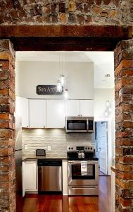 a kitchen with stainless steel appliances and a brick wall at Newly Renovated Historic Savannah Townhome! in Savannah
