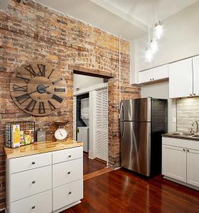 a kitchen with a brick wall with a clock on the wall at Newly Renovated Historic Savannah Townhome! in Savannah
