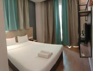 Un dormitorio con una cama blanca con una toalla. en Hotel 99 Bandar Puteri Puchong, en Puchong