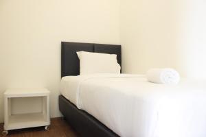 a white bed with a black headboard next to a table at Premium 2BR Tamansari Panoramic Apartment By Travelio in Bandung +12 photos