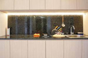 ジャカルタにあるMinimalist and Cozy 2BR Citralake Suites Apartment By Travelioのシンクとカウンタートップのあるキッチン