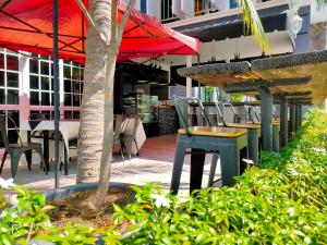 a patio with a table and chairs and a tree at Royale Chenang Resort in Pantai Cenang
