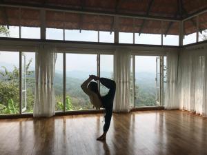 a woman doing a yoga pose in a room with windows at SpiceTree Rajakumari in Munnar