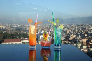 three cocktails sitting on a table with a view of a city at Hotel Crowne Imperial in Kathmandu