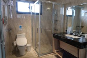 a bathroom with a shower and a toilet and a sink at The HO Hotel in Hsinchu City