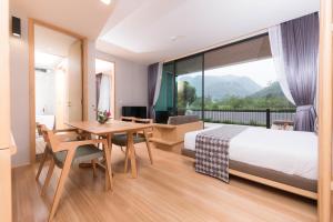 Habitación de hotel con cama, escritorio y mesa. en Zen Next Khao Yai By ZV, en Pak Chong