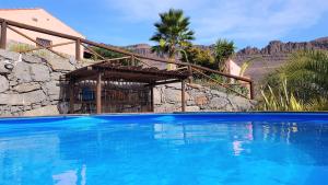 Finca Las Olivas - Unique country house with heated pool في ماسبالوماس: مسبح ازرق كبير امام المنزل