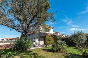 a white house with a tree in the yard at Hotel Calarossa Bay Resort in Porto-Vecchio