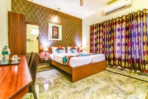a hotel room with a bed, table, and a dresser at FabExpress Nestlay Rooms in Chennai