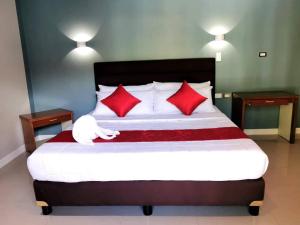 a bedroom with a large bed with red pillows at Charms Hotel in Coron