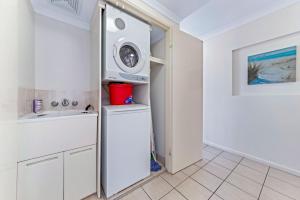 a kitchen with a sink and a washing machine at Airlie Dream in Airlie Beach