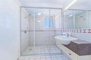 a bathroom with a glass shower and a sink at Airlie Dream in Airlie Beach +9 photos