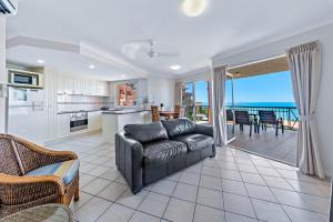 a living room with a couch and a kitchen at Airlie Dream in Airlie Beach