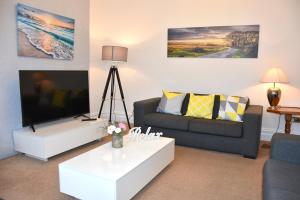 a living room with a couch and a flat screen tv at Cornish Townhouse Central Newquay with Parking - Simply Check In in Newquay