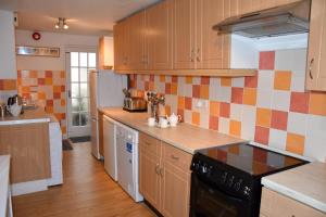 a kitchen with wooden cabinets and a black stove top oven at Cornish Townhouse Central Newquay with Parking - Simply Check In in Newquay