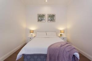1 dormitorio con 1 cama blanca grande y 2 lámparas en Emu at White Gum Lodge, en Fremantle