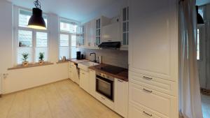 eine Küche mit weißen Schränken, einem Waschbecken und Fenstern in der Unterkunft Ihr Zuhause in Jakobi's Straße in Goslar