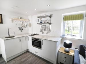 a kitchen with white cabinets and a sink and a window at Owl Cottage in Pwllheli
