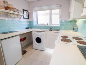 a kitchen with a washing machine and a sink at Beachside and Golf Apartment in Coleraine