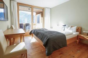 a bedroom with a bed and a desk and a window at Chalet Christl Panorama Appartements in Schruns