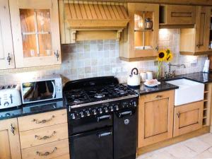 a kitchen with a black stove and wooden cabinets at The Stables in Settle