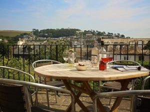 ein Holztisch mit Weinflaschen und Gläsern auf einem Balkon in der Unterkunft Moonrakers, Clarence Street in Dartmouth