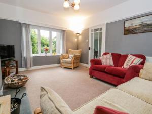 a living room with a red couch and chairs at Crossways in Grange Over Sands