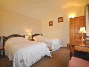 a bedroom with two beds and a table with lamps at Follis Cottage in Weymouth