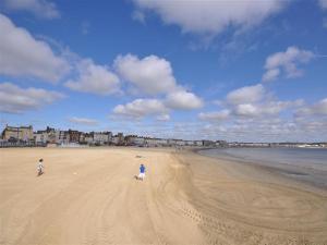 two people walking on a sandy beach near the ocean at Follis Cottage in Weymouth