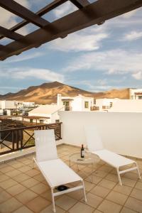 a balcony with two white chairs and a table at Playa Blanca Beach Mate in Playa Blanca