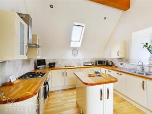 a kitchen with white cabinets and a wooden counter top at Fossil Barn in Chickerell