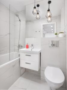 a white bathroom with a toilet and a sink at oompH Warsaw Downtown Apartments in Warsaw