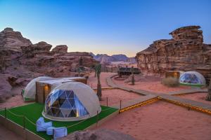 a group of tents in the desert near some rocks at Palmera Camp Wadi Rum in Wadi Rum