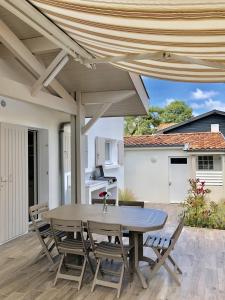 eine Terrasse mit einem Tisch und Stühlen sowie eine Küche in der Unterkunft Villa La Plage Pour 7 Personnes A Proximite Du Port De Plaisance in Capbreton