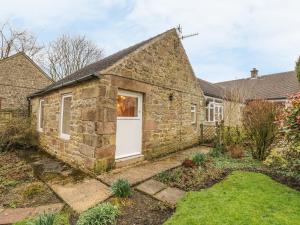 an old stone house with a white door at Barn Croft Cottage in Matlock
