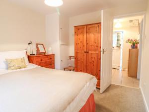 a bedroom with a white bed and a wooden cabinet at Barn Croft Cottage in Matlock