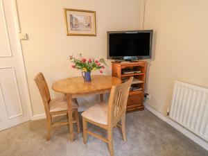 a dining room table with a television and flowers on it at Barn Croft Cottage in Matlock