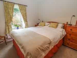 a bedroom with a large bed and a window at Barn Croft Cottage in Matlock