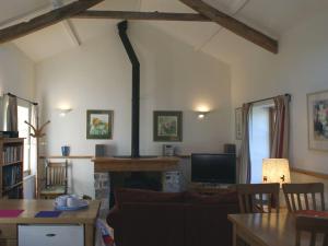 a living room with a fireplace and a table with a television at Mill House Barn in Okehampton