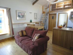 a living room with a brown couch and a kitchen at Mill House Barn in Okehampton