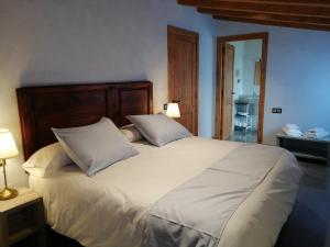 a bedroom with a large white bed with two pillows at Cal Teixidor - La Fusteria in Salo