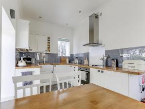 a white kitchen with white cabinets and wooden floors at Poppyfields Stable in Redruth