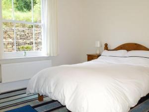 a white bed in a bedroom with a window at Hedgelea in Winkleigh
