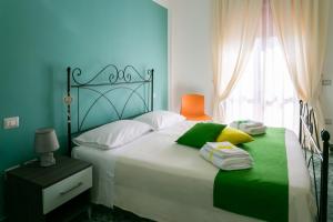 パエストゥムにあるB&B Menta e Limoneのベッドルーム1室(緑と白の枕が備わる大型ベッド1台付)