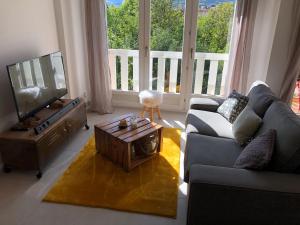 a living room with a couch and a tv and a table at Appartement de charme idéalement situé in Gap