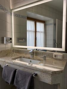 uma casa de banho com um lavatório e um espelho grande em Hotel Lobmeyer em Roding