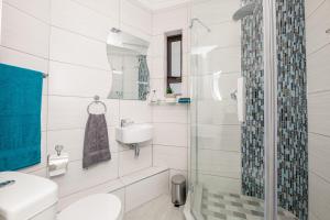 a white bathroom with a sink and a shower at Big Blue Accommodation in Bloubergstrand +17 photos