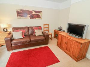 a living room with a brown leather couch and a flat screen tv at Eskholme Lodge in Ravenglass