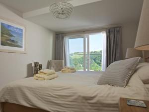 Un dormitorio con una gran cama blanca con ventana. en 2 Hamstone Court, en Salcombe