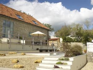 a building with a patio with a table and an umbrella at Leys At Valley View Farm in Lyme Regis